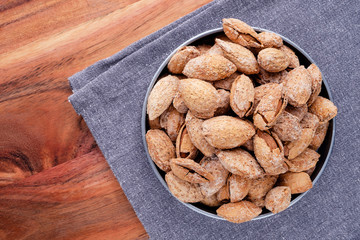 nuts snack salted almonds in shell in metal plate on wooden table top view