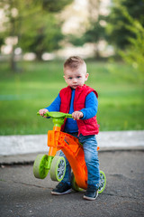 little baby boy in fashionable clothes on a scooter