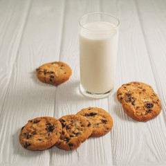 glass of milk and cookies with chocolate on a white wooden background