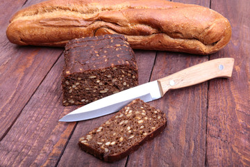 Sliced black bread and knife on the old wooden plank