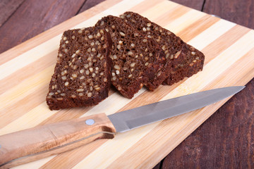 Sliced black bread and knife on the old wooden plank