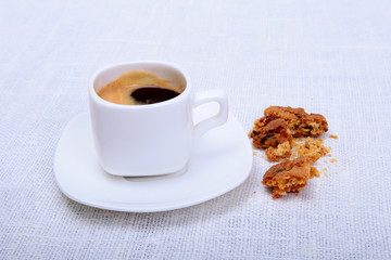 Cup of espresso coffee on white plate with pieces cookie on white background