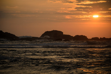 Красивый закат над океаном. Камни в океане на фоне заката