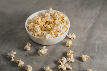 popcorn in a white plate on a concrete gray background