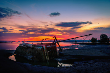 The old fishing boat capsized on sea at sunset in Phuket, Thailand.