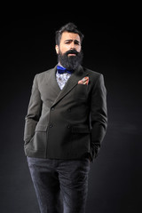 long bearded man in fashion suit on black background
