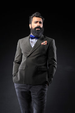 long bearded man in fashion suit on black background