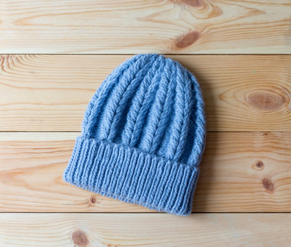 Blue hat knitted by hand from wool on wooden background