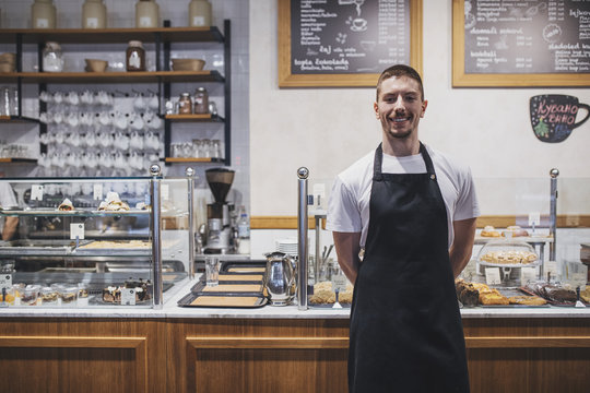 Portrait of young handosme Caucasian waiter standing in coffee shop. - Powered by Adobe