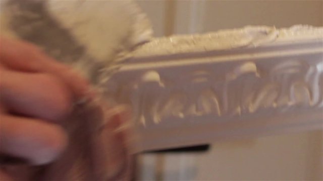 Ceiling moldings/Man puts glue on ceiling with plaster cornices