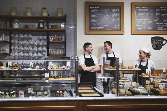 Bakers and waiters working together at coffee shop and smiling.