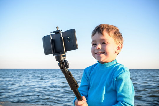 Young boy doing a selfie at the beach, kid happy and smiling loo