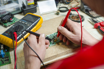 man hands closeup repair electronic device using Multimetr. tools