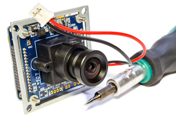 Electronic module with lens for surveillance camera and screwdriver on a white background - obrazy, fototapety, plakaty