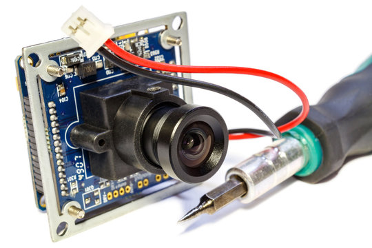 Electronic Module With Lens For Surveillance Camera And Screwdriver On A White Background