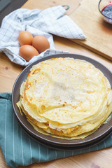 Ready traditional thin pancakes on a plate with ingredients and decor.