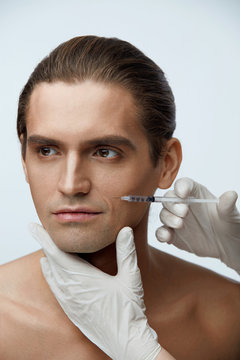 Beautician Doing Cosmetic Injection In Male Patient Face