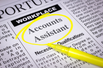 Fototapeta premium Accounts Assistant - Newspaper sheet with ads and job search, circled with yellow marker, Blurred image and selective focus