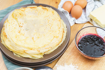 Stack of ready pancakes on a plate with jam and decor. 