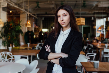 Portrait of a young cute brunette girl business in the interior hipster cafes. Long hair.