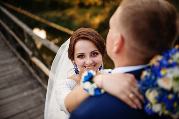 Obraz premium Cheerful wedding couple on wooden bridge at sunset.