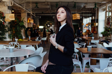 Portrait of a young cute brunette girl business in the interior hipster cafes. Long hair.