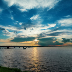 Fototapeta na wymiar dramatic clouds in sunset over river