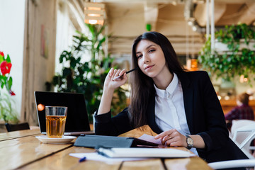 Fototapeta premium Beautiful brunette using laptop and tablet hipster coffee shop with a wooden table.