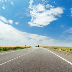 asphalt road to horizon and blue sky with clouds over it