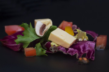 on lettuce leaves a handful of cheese and tomatoes on a dark background