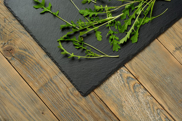 Fresh juicy arugula on a black stone background with copy space