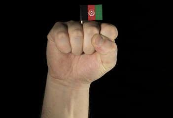 Man hand fist with Afghan flag isolated on black background