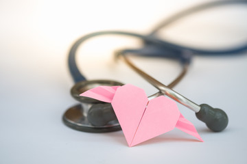 Pink paper heart and stethoscope on white background, concept of Valentine's day and healthcare