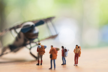 Miniature people : travellers standing on world map in front of vintage airplane for travelling around the world,  exploring on earth background concept.