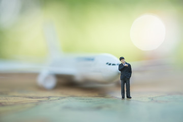 Miniature people : businessman standing on world map in front of airplane waiting for boarding, business concept,  exploring on earth background concept.