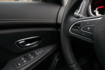 Fototapeta na wymiar Mobile phone control unit on the steering wheel and door trim.