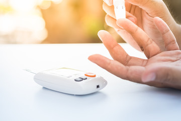 Close up of asian man's  hands using lancet on finger to check blood sugar level by glucose meter, Healthcare medical and check up, diabetes, glycemia, and people concept