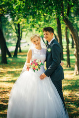 portrait the bride and groom on the background of the park alley