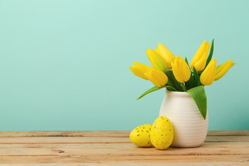 Easter holiday concept with tulip flowers and eggs decorationas on wooden table over mint background
