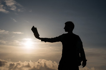 Silhouette of man reading book at sunset nanute