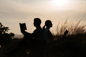 Fototapeta na wymiar Silhouette of man and girl read book at sunset