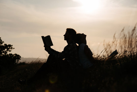 Silhouette of man and girl read book at sunset