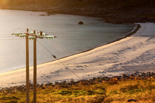 Strommast zerschneidet den Blick auf einen norwegischen Strand im Abendlicht – Nykan, Langoya, Vesteralen