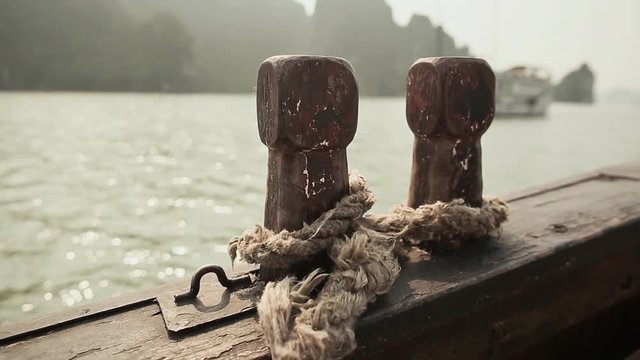 Two wooden bollards with an old rope on a moving ship at sea