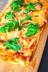 Pizza with basil and cheese on a wooden board.