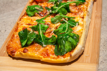 Pizza with basil and cheese on a wooden board.
