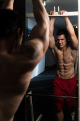 Fototapeta na wymiar Muscular Man Flexing Abdominal Muscles In Gym