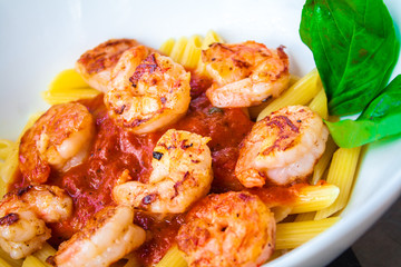 Pasta with fresh sauce and shrimps on a white plate background.