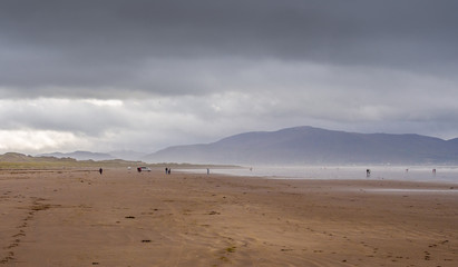 Fototapeta na wymiar Visitors taking a walk on the beautiful Inch beach, Dingle bay, Republic of Ireland.
