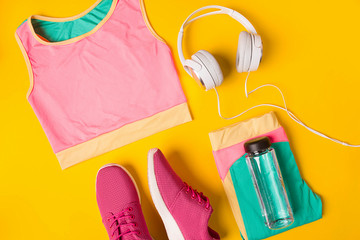 Sport equipment. Sneakers and bottle of water on yellow background